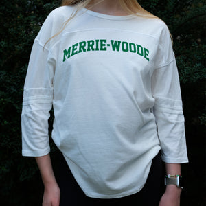 Blonde girl wearing a white, 3/4 sleeve t-shirt that says "Merrie-Woode" across the chest in green lettering. 