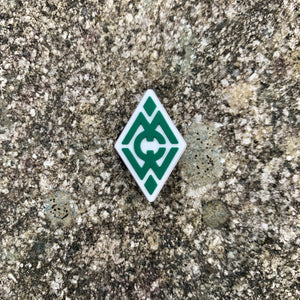 1 inch tall, rubber Croc charm of Camp Merrie-Woode's diamond logo, which is the letters C,M,W in green on top of a white diamond shape.
