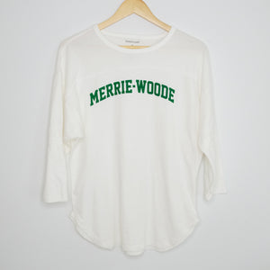 A white, 3/4 sleeve t-shirt that says "Merrie-Woode" across chest in green lettering hanging on a wooden hanger. 