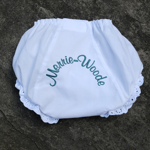 White diaper cover, with ruffles on the edges, that says 