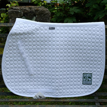 Load image into Gallery viewer, White saddle pad with the rectangle Merrie-Woode logo in the bottom right corner, that shows a horse, its rider, and two girls on a dock. Saddle pad is sitting on a metal bench in front of green leaves.
