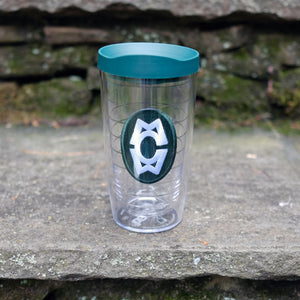 Clear Tervis tumbler with a green lid featuring the Camp Merrie-Woode oval logo, which has the initials "CMW." Tumbler is sitting on a stone step.